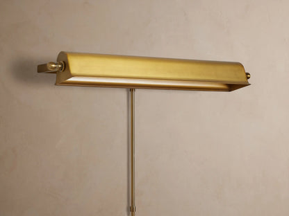 Antiqued metallic Tremont Picture Light Sconce on a textured wall, glowing warmly downwards.