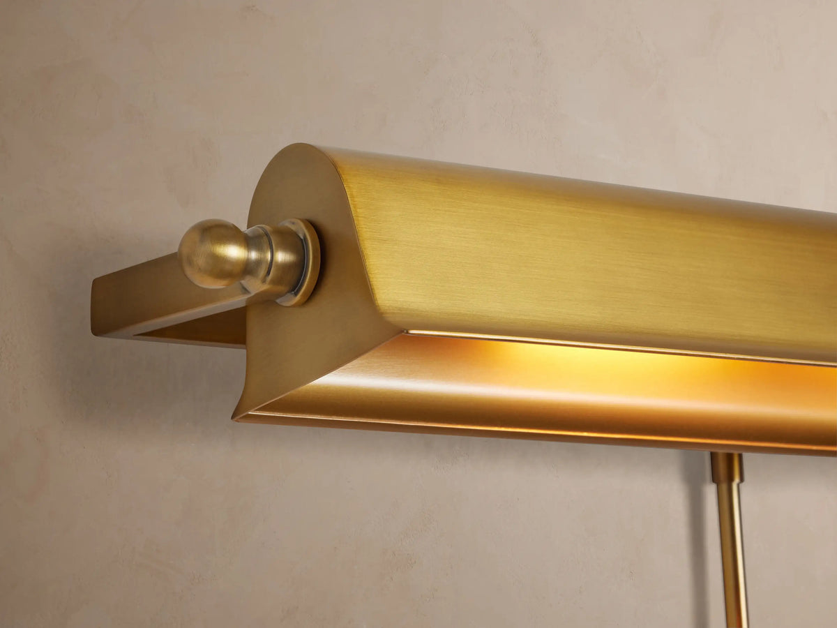 Tremont Picture Light Sconce: horizontal antiqued metallic finish fixture mounted on a light beige wall.