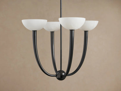 Saguaro Chandelier with four glowing white alabaster bowl shades on dark, upward-curving arms against a brown wall.