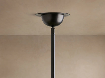 Close-up of Saguaro Chandelier with multiple glowing, natural alabaster bowl shades on dark, curved iron arms against a beige wall.