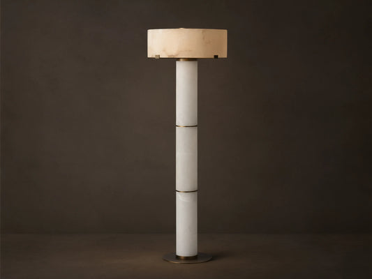 Chayla Floor Lamp: Tall, segmented white alabaster column, glowing cylindrical shade with natural patterns, antique brass accents, wood floor.