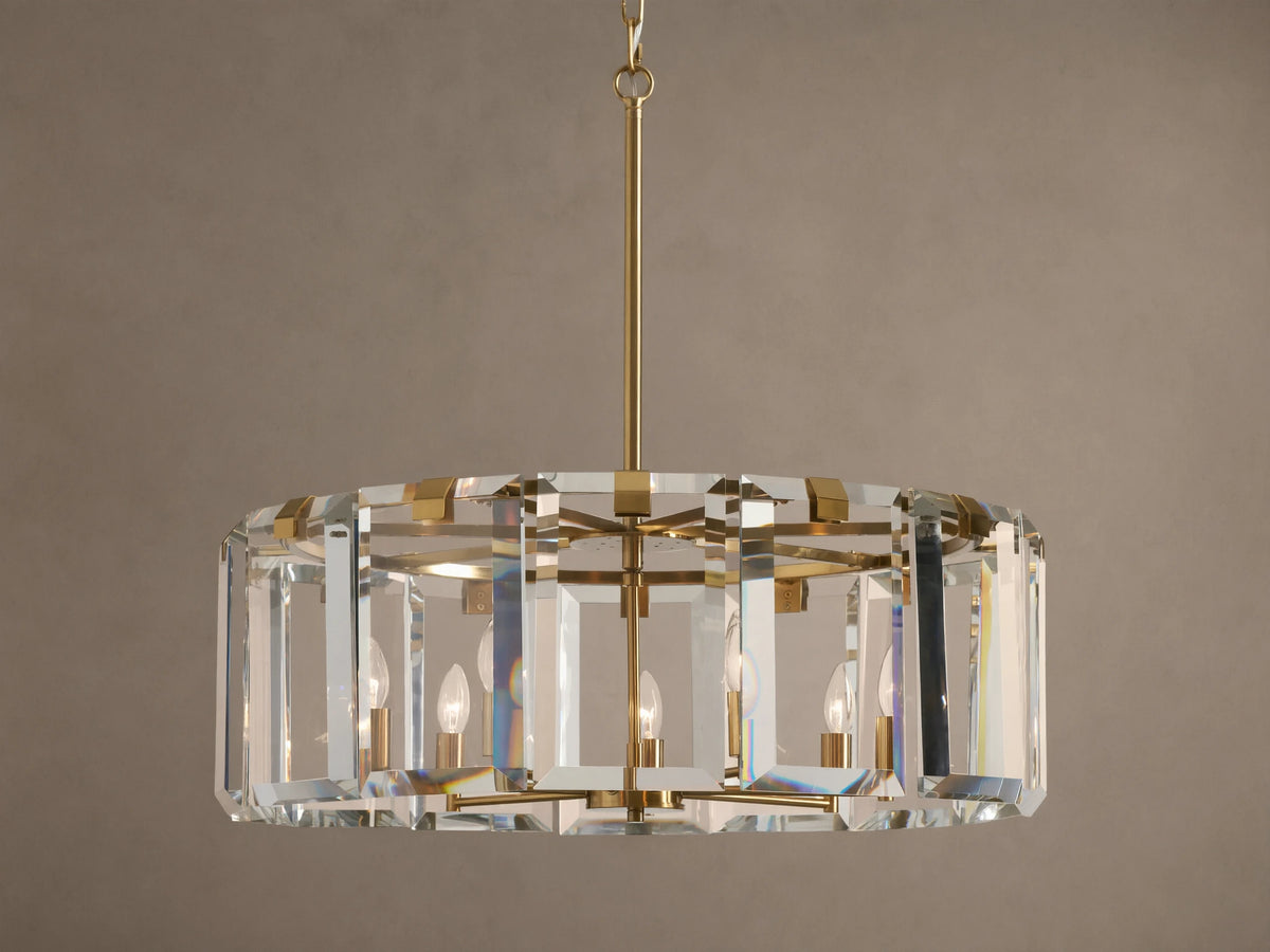 Round Amaya Chandelier with brass frame & thick, clear crystal panels, showcasing five candelabra bulbs, against a plain wall.