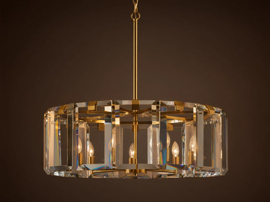 Round Amaya Chandelier with brass frame & thick, clear crystal panels, showcasing five candelabra bulbs, against a plain wall.