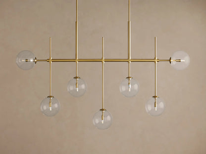 Roscoe Linear Chandelier: Brass-finished linear frame with 7 clear glass globes containing bulbs, 5 hanging, 2 horizontal.