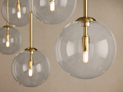 Roscoe Linear Chandelier, brass-finished, with 7 clear glass globes on a horizontal bar and hanging vertically, beige background.