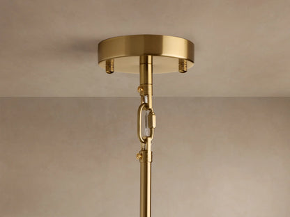 Close-up of Apollo Round Chandelier with polished brass arms radiating from center, holding clear spherical glass shades with glowing bulbs.
