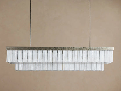 Cameron Rectangular Chandelier with antique silver frame & two tiers of glowing white selenite blades, suspended on a brown wall.