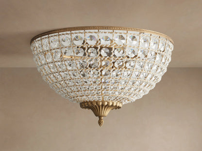 Poppy Flush Mount. Dome-shaped fixture with rows of clear faceted crystals and antique brass accents, glowing warmly on a ceiling.