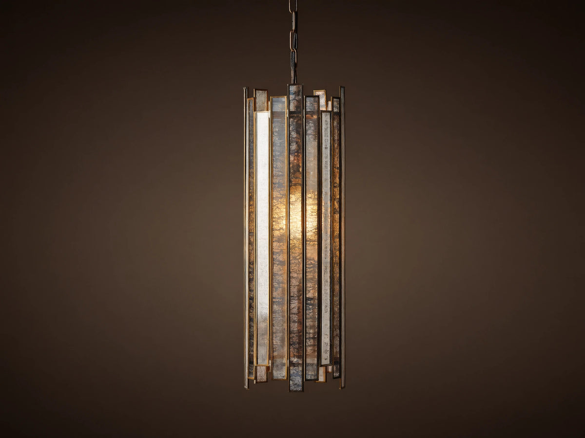 Laila Pendant, a cylindrical light with vertical antiqued mirrored-glass panels and an antique copper frame, glowing warmly.
