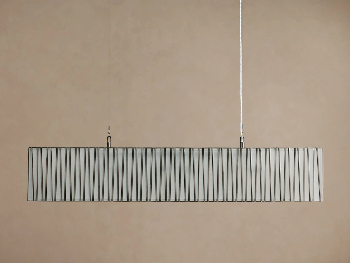 Horizontal Jeunet Rectangular Chandelier in Nickel, hanging against a tan wall, showing glowing white panels through vertical nickel bars.