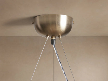Close-up of a glowing Jeunet Round Chandelier with a round brass frame and illuminated rectangular glass panels.