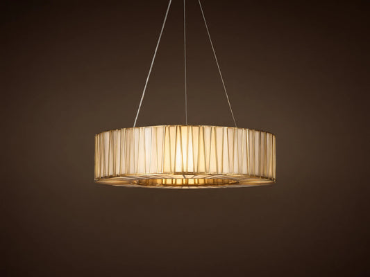 Jeunet Round Chandelier with antiqued brass geometric frame, illuminated cream glass panels, hanging from cables on a warm wall.