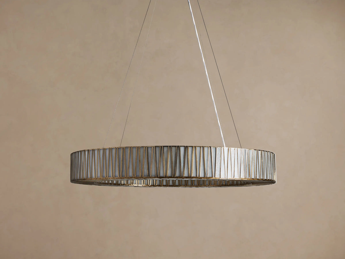 Jeunet Round Chandelier, antiqued brass finish, circular frame with many vertical glass panels glowing softly, hanging from above.
