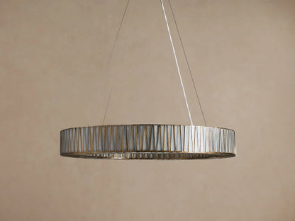 Jeunet Round Chandelier, antiqued brass finish, circular frame with many vertical glass panels glowing softly, hanging from above.