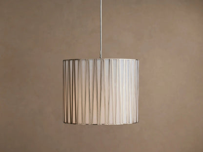 Hanging Jeunet Pendant light, cylindrical white shade with vertical antiqued nickel metal strips, softly glowing.