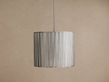 Hanging Jeunet Pendant light, cylindrical white shade with vertical antiqued nickel metal strips, softly glowing.