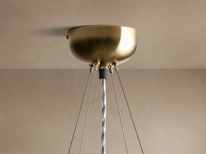 Close-up of a round Jeunet chandelier with vertical frosted glass panels and antiqued brass frames, glowing warmly.