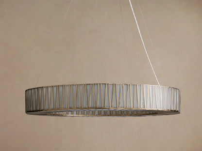 Jeunet Round Chandelier with an antiqued brass geometric frame and glowing white inner diffuser, suspended by thin cables.