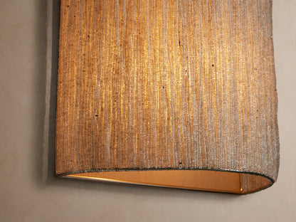 Vertical Romilly Beaded Sconce covered in individually strung light silver-toned glass beads, creating fine vertical strands, on a light brown wall.