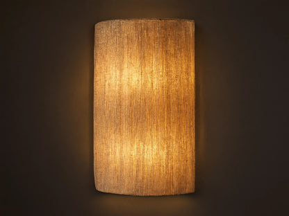 Romilly Beaded Sconce, vertical, elongated, warm light shining through its textured, light-colored strung glass beads on a neutral wall.