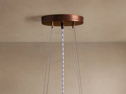 Romilly Tiered Chandelier close-up. Curved tiers of shimmering bronze glass beads hang vertically, glowing with warm light.