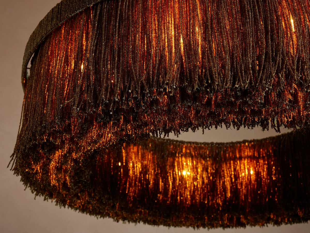 Close-up, angled view of Romilly Round Chandelier with two tiers of shimmering dark glass beads, warmly lit from within.