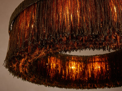 Close-up, angled view of Romilly Round Chandelier with two tiers of shimmering dark glass beads, warmly lit from within.