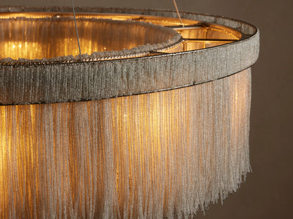 Close-up of Romilly Round Chandelier. Warm light glows through delicate strands of light glass beads on its circular, metallic frame.