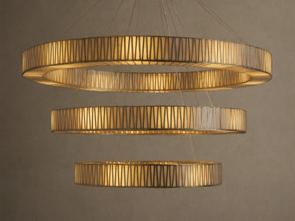 Jeunet 3-Tier Round Chandelier, illuminated with warm golden light, featuring three cascading rings of antiqued brass and textured glass.