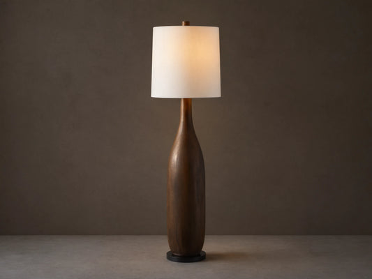A tall Briar Floor Lamp with a dark espresso, slender wooden base and a glowing white linen cylinder shade on a wooden floor.