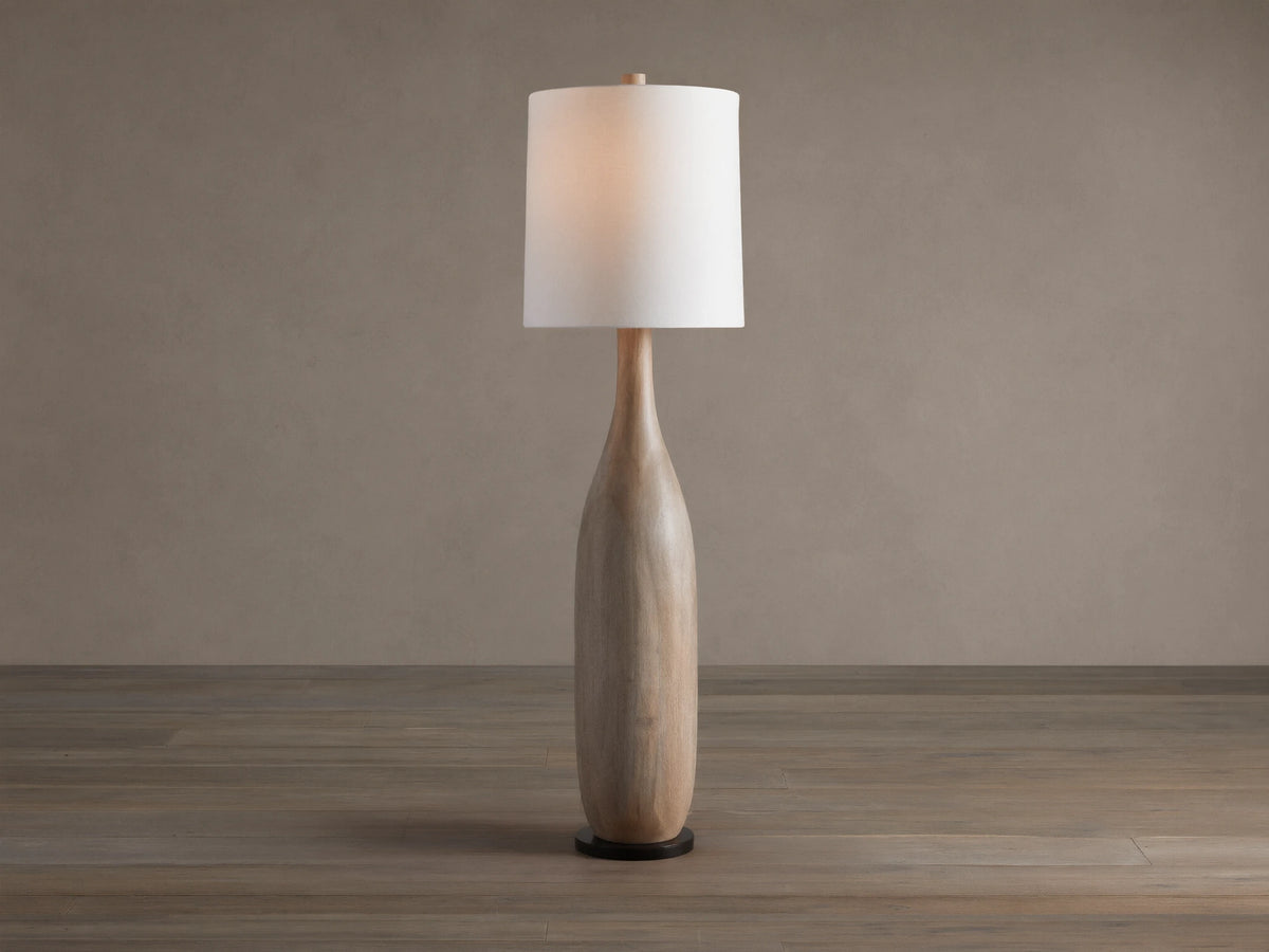 Briar Floor Lamp: natural wood, bottle-shaped base, with a white cylindrical linen shade, standing upright on a wood floor.