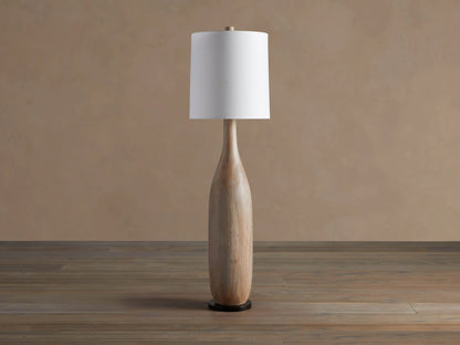 Briar Floor Lamp: natural wood, bottle-shaped base, with a white cylindrical linen shade, standing upright on a wood floor.