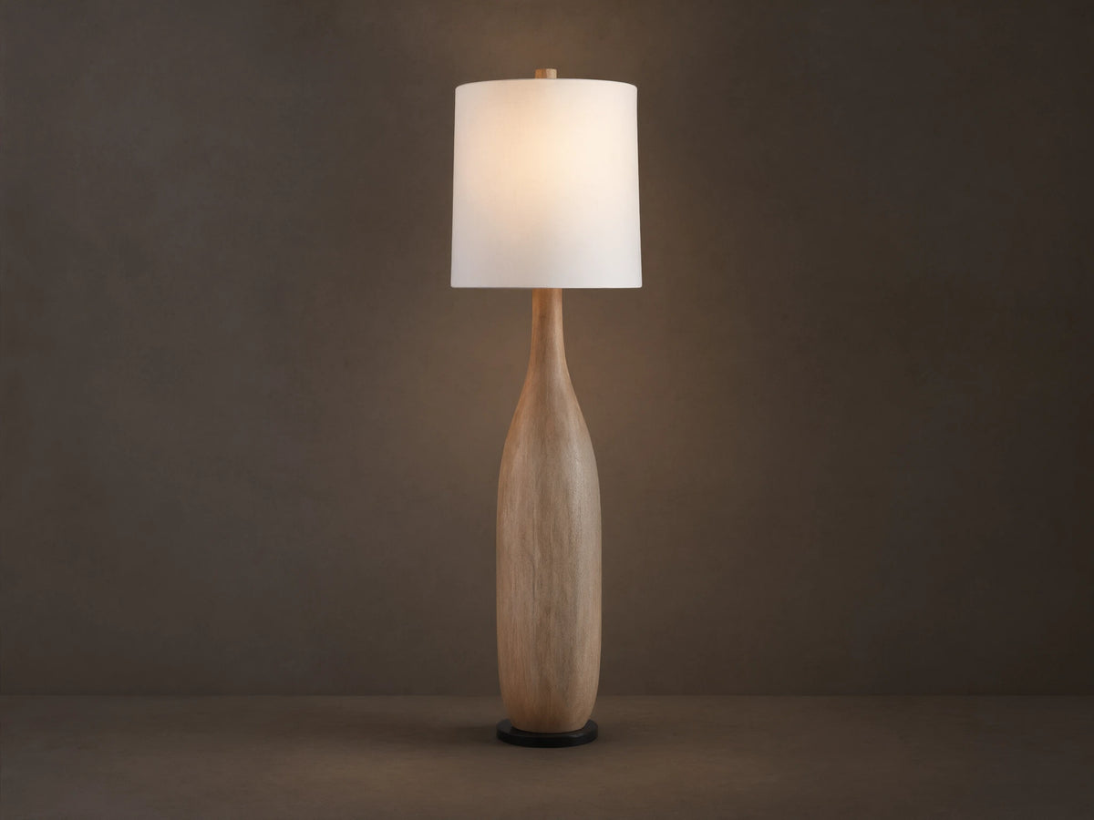 Briar Floor Lamp: natural wood, bottle-shaped base, with a white cylindrical linen shade, standing upright on a wood floor.