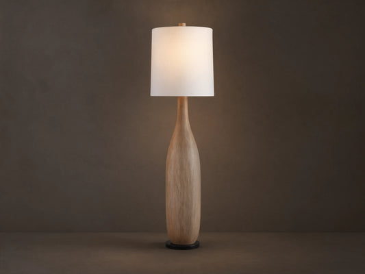 Briar Floor Lamp: natural wood, bottle-shaped base, with a white cylindrical linen shade, standing upright on a wood floor.