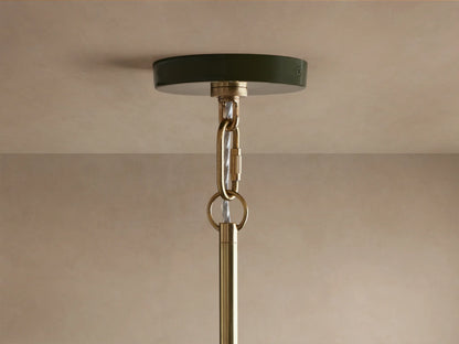 Close-up of Bonham Pendant: dark green powder-coated exterior, glossy brass interior reflecting warm light from three bulbs.