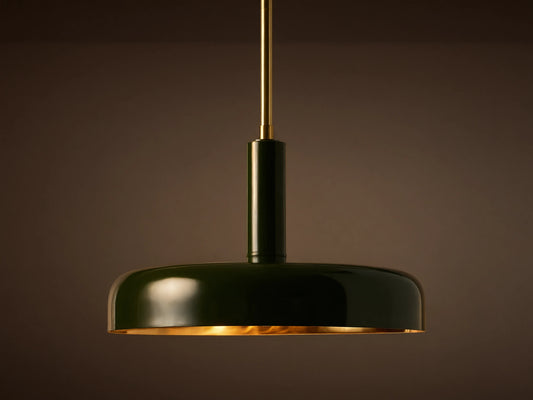 Bonham Pendant: Dark green dome-shaped light with a brass interior hangs from a brass rod against a textured warm grey wall.
