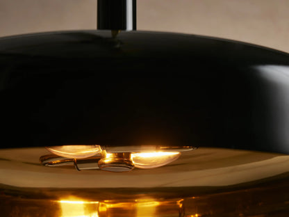 Bonham Pendant: Sleek black dome pendant light with a polished brass interior and hanging rod, viewed against a neutral wall.