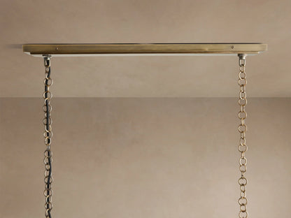 Close-up of Holt Linear Chandelier with glowing bulbs, showing the detailed antiqued brass and black metal frame.