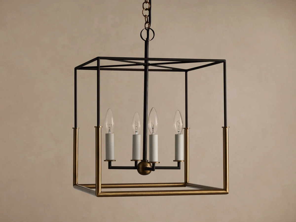 Holt Square Pendant, a square, open-cage light fixture with black and antiqued brass frames, featuring four clear candle-style bulbs.