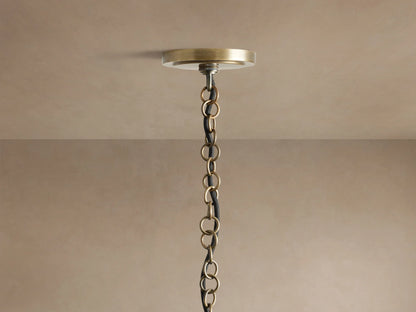Holt Square Pendant: Close-up of four glowing candelabra bulbs in white sleeves on an antiqued brass and black iron frame.