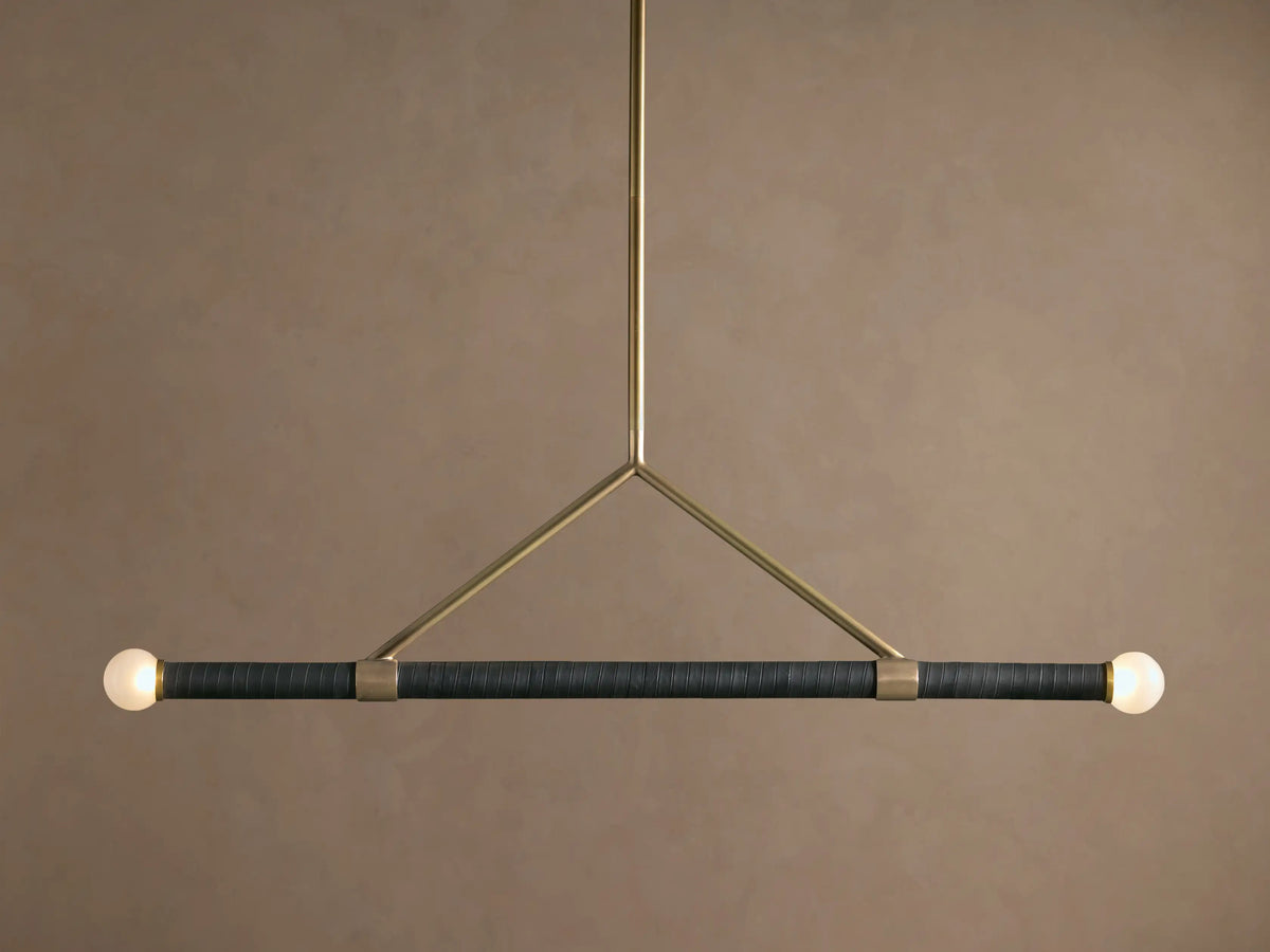 Randall Leather Pendant: Dark leather-wrapped horizontal bar with two frosted globe bulbs, suspended by a burnished brass frame.