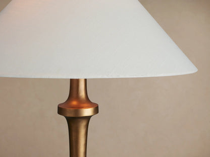 Murphy Floor Lamp with a brass finish, conical base, slender stem, and white tapered linen shade.
