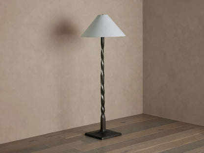 Jayne Floor Lamp: Tall, dark pewter-finished twisted metal base with a white conical linen shade, casting a warm light.