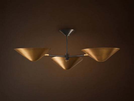 Simms Flush Mount light fixture with three golden, cone-shaped shades extending from a dark central rod, mounted on a ceiling.