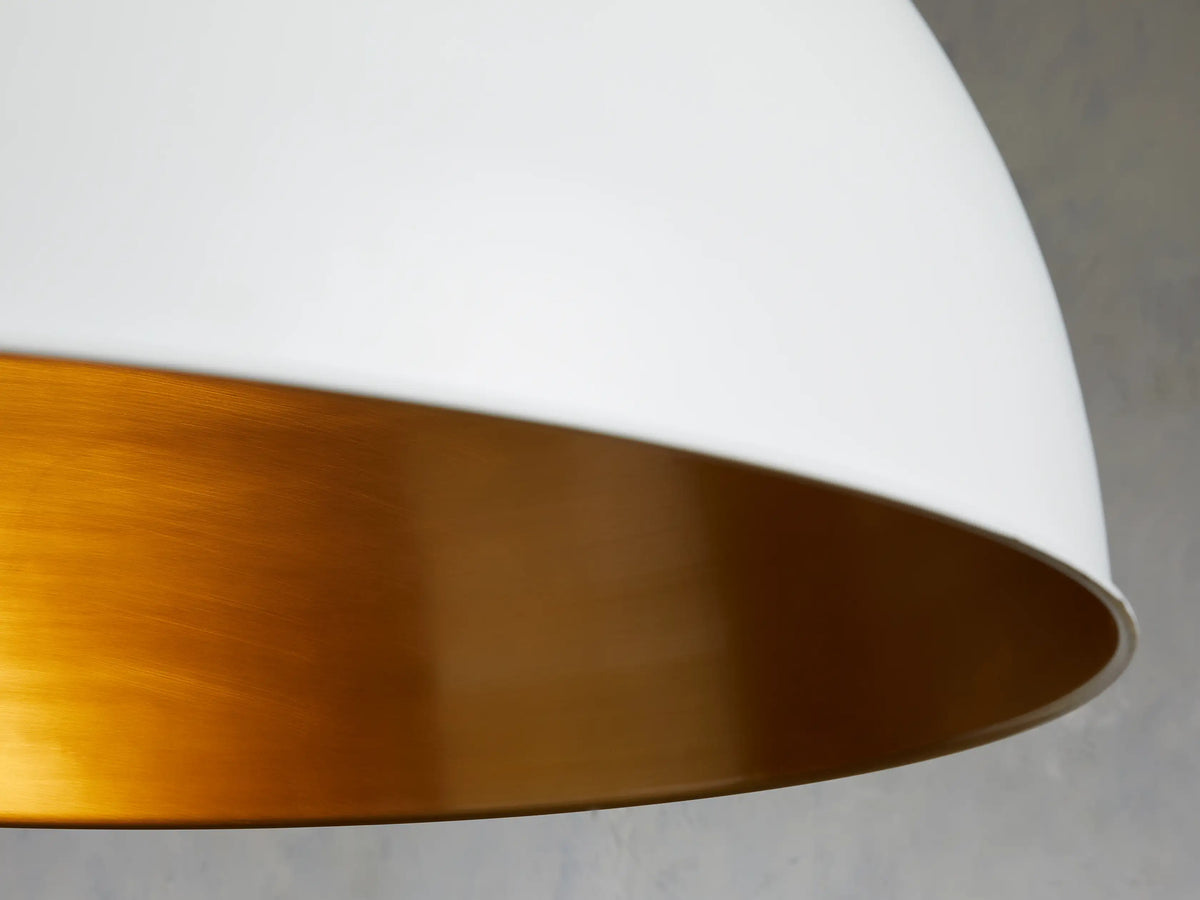 Watley Dome Pendant with a white exterior and polished antique brass interior, showcasing a smooth, rounded design.