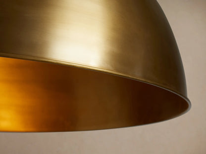 Watley Dome Pendant: A polished antique brass dome-shaped light fixture, suspended from a chain against a neutral background.