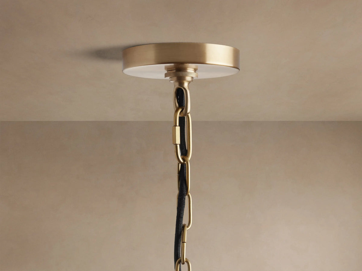Close-up of a Watley Dome Pendant light. It has a brushed antique brass exterior and a highly polished, reflective gold interior.