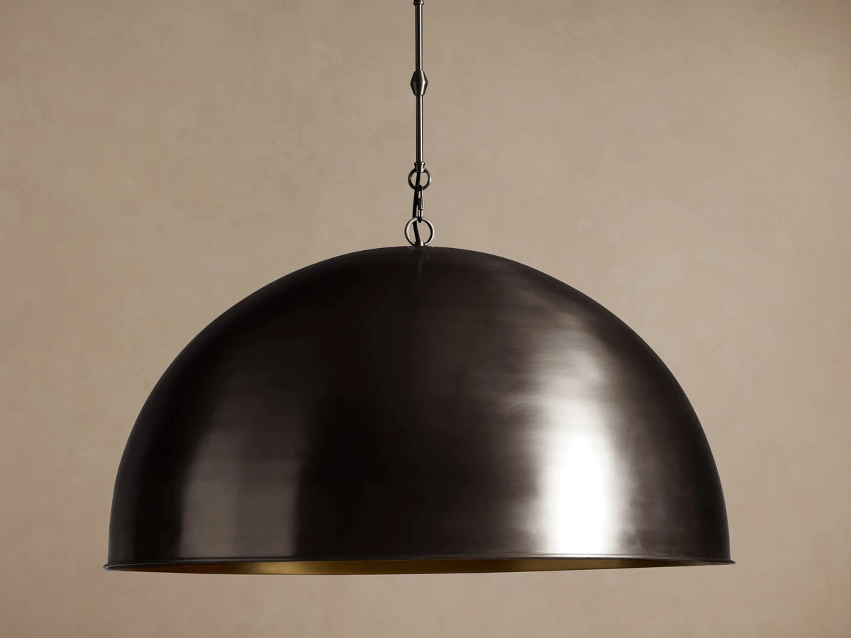 Watley Dome Pendant: Large dark dome with a polished, glowing antique brass interior, suspended from a dark chain.