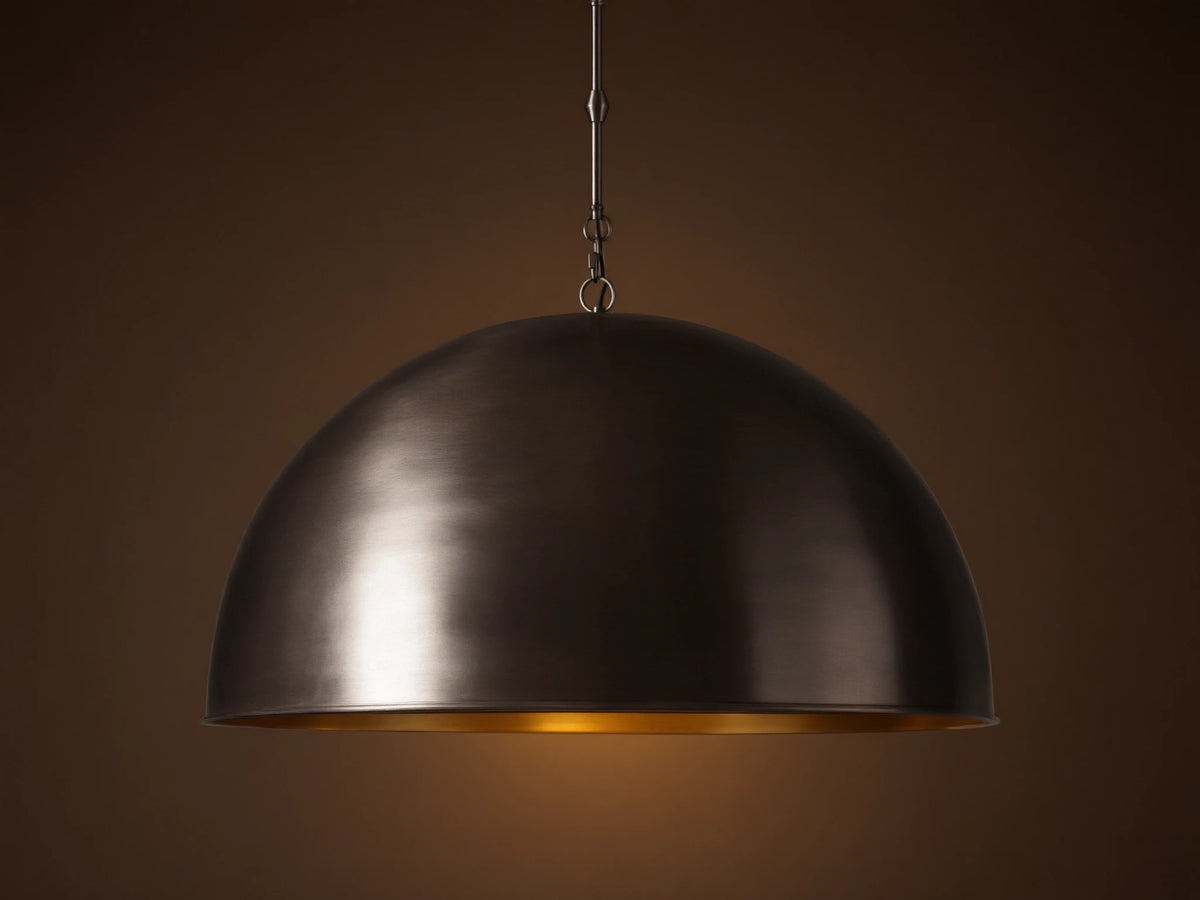 Watley Dome Pendant: Large dark dome with a polished, glowing antique brass interior, suspended from a dark chain.