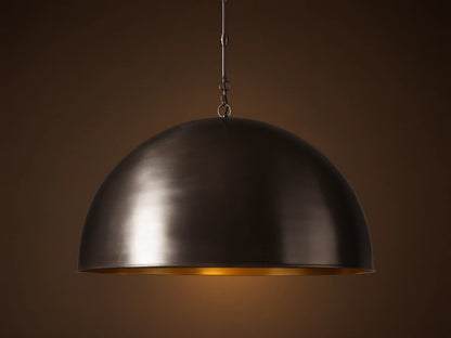 Watley Dome Pendant: Large dark dome with a polished, glowing antique brass interior, suspended from a dark chain.